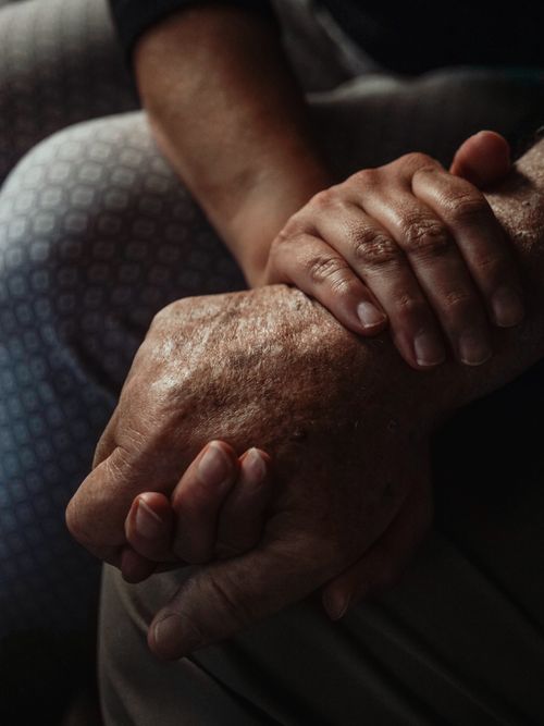 A caring hand holding the hand of an older adult